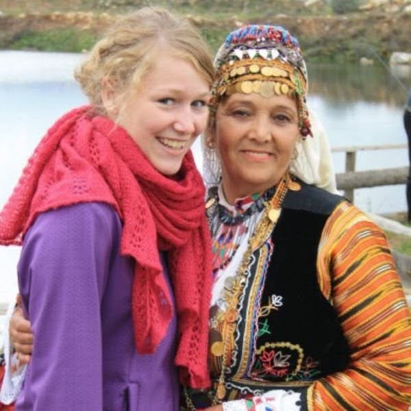 An exchange student smiles with a woman dressed in traditional Bulgarian clothing.
