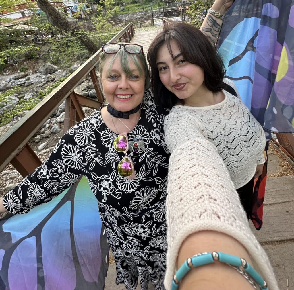 A host mother and her exchange student standing together on a bridge wearing butterfly wings.