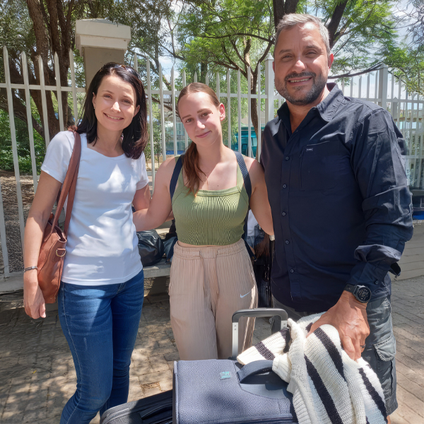 A couple smiles with their exchange student as they say goodbye