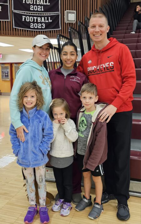 Smiling girl exchange student with her host family dad, mom, and siblings