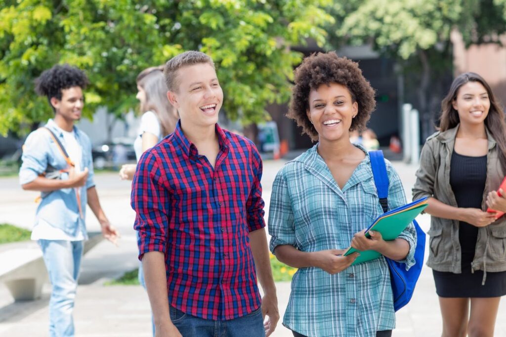 High school students walking together outdoors smiling and talking, representing cultural exchange and connection