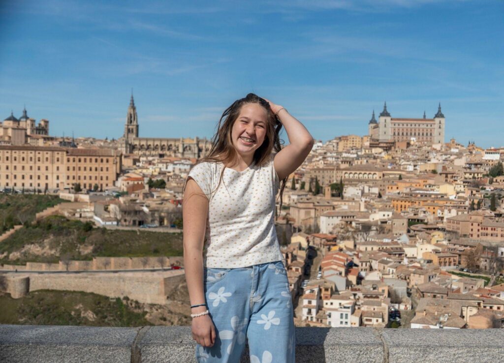 Young study abroad student smiling in front of historic city skyline in Spain
