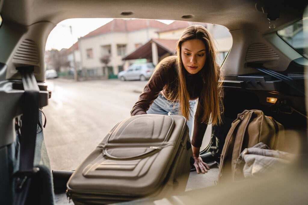 Study abroad student loading packed luggage into car before departure
